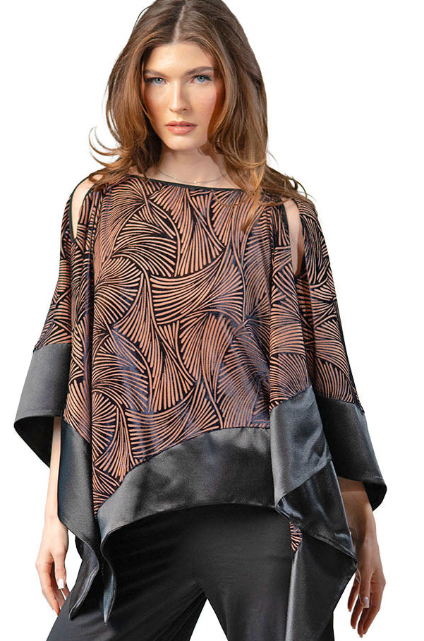 Woman wearing a patterned top and black pants on a white background