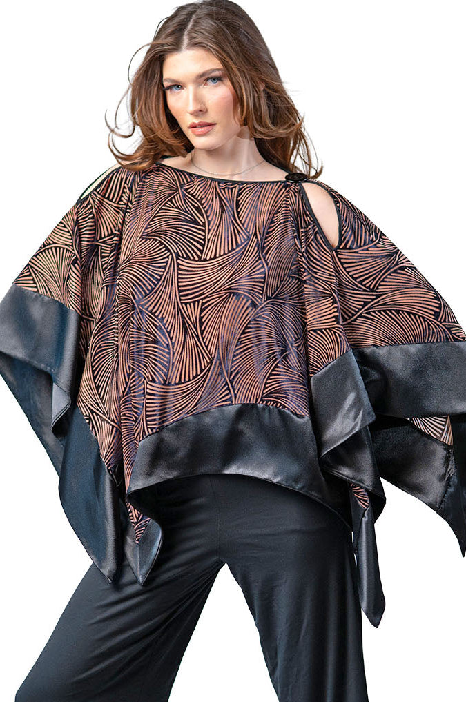 Woman wearing a patterned poncho over a plain top with black pants on a white background