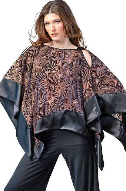 Woman wearing a patterned poncho over a plain top with black pants on a white background